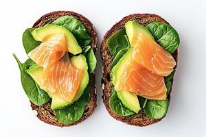 Two slices of whole wheat bread topped with smoked salmon, avocado and spinach photo
