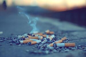 Cigarette butts and ash creating pollution on ground photo