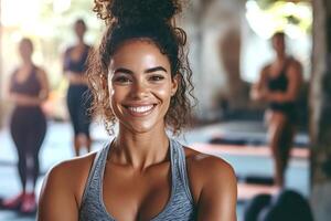 Smiling fitness instructor posing in a gym with students training photo