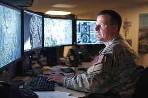Military operator working on multiple screens showing maps and data visual photo