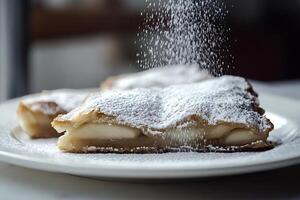 Pastry chef sprinkling icing sugar on delicious apple turnover photo