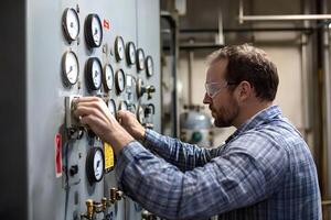 Engineer working on control panel with gauges in industrial setting photo