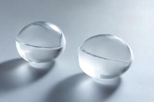 Two glass spheres resting on a textured surface, casting subtle shadows photo