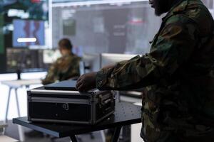 Military staff in a high tech command post gathers intelligence for crucial defense operation, working with satellite radar systems on computers. Supporting troops in field missions. photo