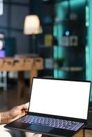 Remote employee at home on couch inputting data on isolated screen laptop. Man in apartment trying to complete job tasks before deadline, typing on mockup notebook device photo