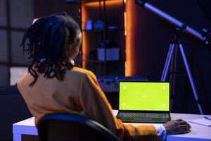Freelancer in living room office using chroma key laptop to answer emails from business associates. Remote worker typing on isolated screen device keyboard, solving tasks in apartment photo