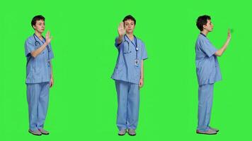 Health specialist with blue scrubs showing stop sign in studio, standing against greenscreen backdrop. Nurse expressing denial and refusal with warning forbidden symbol, denying something. Camera A. photo