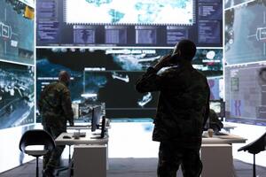 Soldier sharing important battlefield information on phone call, works on intelligence gathering and data processing in a secure office environment. Maintaining operational efficiency. photo