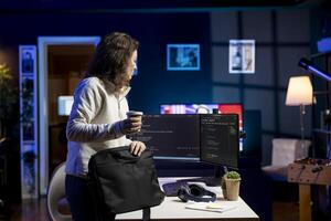Admin with disposable cup of coffee entering office to implement security measures, protecting company systems and data. IT staff member starting job shift, testing and debugging code photo