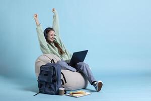 Joyous woman using laptop, displaying satisfaction, feeling joyful, isolated over studio background. Lively upbeat person celebrating achievement, showing positive demeanor while holding notebook photo