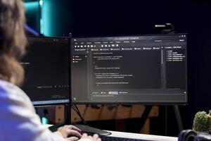 Engineer working from home developing software in Java programming language using computer monitor. Programmer in apartment solving coding problems using desktop PC display photo