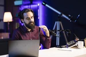 Entertaining content creator in studio films tablet review for tech enthusiasts. Viral online star hosts technology internet show, unboxing digital portable device, feeling impressed by thinness photo