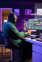 Music composer plays electronic keyboard piano keys and recording new tracks, creating audio recordings before launching music. Artist producer uses synthesizer and amplifier, post production. photo