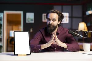 Tech guru presenting mockup tablet to interested viewers, filming with professional microphone. Influencer reviewing isolated screen digital device, recording with specialized gear photo