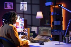Software developer writes code on laptop screen while in apartment office using Java programming languages. Programmer remotely working on fixing database errors while working from home photo