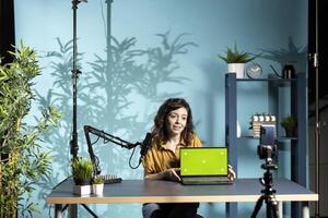 Smiling tech professional assessing isolated screen laptop performance, talking about components used inside. Joyous content creator shooting mockup notebook review for online channel photo