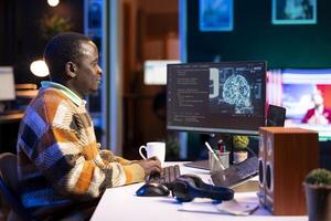 African american worker at desk using personal computer for programming and data analysis. Male networking expert working at home, manages information technology and data center on pc. photo