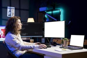 Cybersecurity expert using isolated screen computer to look for security vulnerabilities and injected malware. Programmer installing fortified code on mockup PC and laptop to prevent cyber attacks photo
