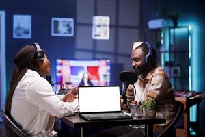 Two people having conversation while laptop displays blank copyspace mockup template. Portable computer showing isolated white screen template, advertising a online streaming platform. photo