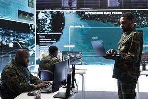 Soldiers in a modern command center analyze live data from cctv radar sources, including satellite feeds and surveillance systems. Intelligence to support strategic planning and military operations. photo