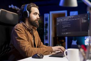 IT developer hearing podcasts while fixing vulnerabilities in software enabling hackers to compromise operating system. Cybersecurity expert enjoying audiobooks, using PC to patch security exposures photo