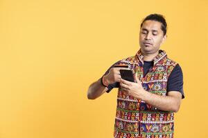 Man looking at debit card to read banking account needed for doing online purchases, isolated over studio background. Man does internet shopping using cellphone, taking advantage of promotions photo
