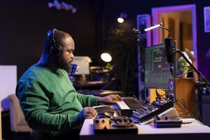 Music composer adding tracks as sound effects for a new song, recording sounds on electronic piano synthesizer. Songwriter audio technician editing and mixing tunes on software. photo