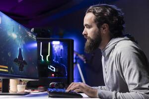 Man relaxing by playing science fiction galaxy videogame with friends on PC in RGB lit apartment late at night. Focused gamer playing with teammates, shooting enemies in online multiplayer shooter photo