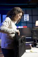 Programmer closing backpack, leaving home office after filtering malicious traffic from cybercriminals. Woman finishing job shift after being done with preventing malware, camera B photo