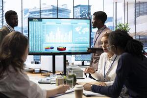 Team of workers presenting infographics and sales numbers on an interactive board, boardroom activity. Diverse group of professionals engages in a project management meeting for growth. photo