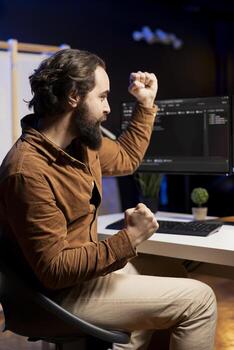 Happy programmer celebrating after managing to secure company servers from virus attacks. Cheerful IT remote employee throwing fist in air from excitement after building firewalls protecting data photo