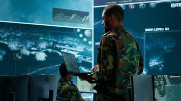 Team of military specialists operate in a secret service command post, managing surveillance systems and data protection to ensure the safety and security of classified information. Camera A. photo