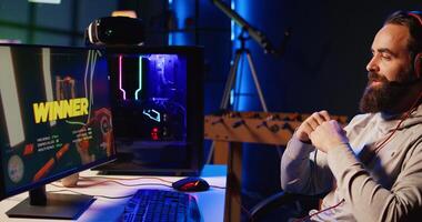 Happy gamer feeling relieved after finally receiving winner screen for killing all enemies in first person shooter. Satisfied player congratulating himself after finishing videogame photo