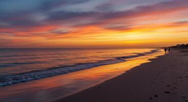 A beautiful sunset on the beach with people walking on the sand photo
