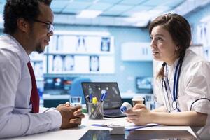 Medical expert discusses test results with a patient in a healthcare setting, utilizing diagnostic tools and computer technology for accurate medical analysis and consultation. photo