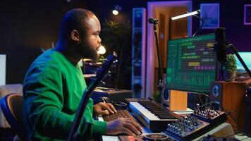 Creative songwriter singing a melody and playing guitar, signal processing technology with digital audio software. Artist producer creating music with acoustic instrument and console. Camera B. photo