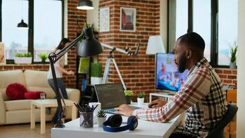 African american software developer works on programming code on a laptop in remote workspace. Productive IT engineer working on coding, software design and internet security innovation. Camera A. photo