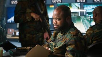 Counterintelligence specialist in military HQ base gathering information on enemy troops. African american agent in base of operations doing assessment of enemy vulnerabilities, tracking, camera A photo