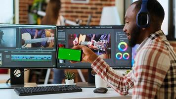 African american man edits a music at his home office next to copy space screen, using editing software and dual monitors. Solving production and freelancing tasks. Camera B. photo