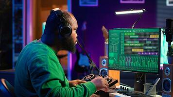 Talented musician mixing and mastering songs on a console, twisting pre amp knobs to add sound effects in post production. Producer composing tracks for album, working in home studio. Camera A. photo