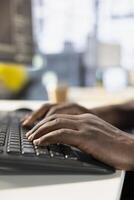 Startup employee sitting at desk in office, typing on keyboard, solving project with deadline approaching. Close up of person writing code at computer in workspace, solving tasks during job shift photo