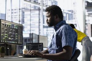 Data scientist at work creating machine learning models that can process and analyze data to improve and automate decision making processes. African american IT expert programming in office using PC photo