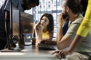IT staff members gathered together to conduct code review to fix bugs, identifying technical issues with artificial intelligence company software. Team coworkers doing brainstorming, optimizing code photo