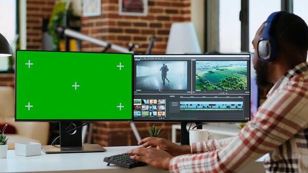Male filmmaker editing a project in a modern color grading software, using copy space screen. Young man employee works on dual monitors during creative process of production. Camera B. photo