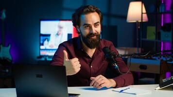 Content creator adjusting professional microphone in studio before starting recording for online vlogging channel. Man in neon lit home studio using equipment for vlog shooting, camera A photo