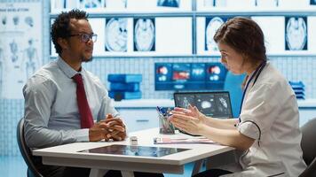 Female doctor and patient engage in a medical consultation with diagnostic tools and x ray imaging visible on the screen. Emphasizing modern healthcare practices and medical research. Camera A. photo