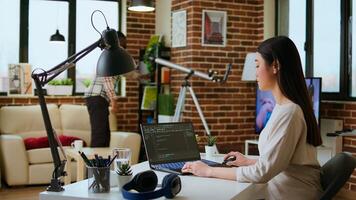 Professional asian software engineer is working remotely typing code on a laptop, using programming language. Woman works on cloud computing, software projects in a digital environment. Camera A. photo