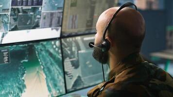 Army specialist working in war room operating surveillance tech, evaluating target data. Close up on dispatcher doing job in HQ base of operations, engaging enemy forces, camera A photo