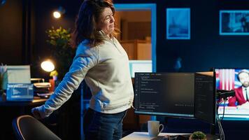 Programmer doing software quality assurance, stretching arms behind back after reading source code, feeling fatigued. IT expert takes break from work to relax muscles after inspecting coding, camera A photo