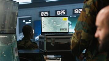 Air force combat control agent performing tactical level surveillance in war room using laptop. Military expert in base of operations using radar on notebook to look at assault zones, camera A photo